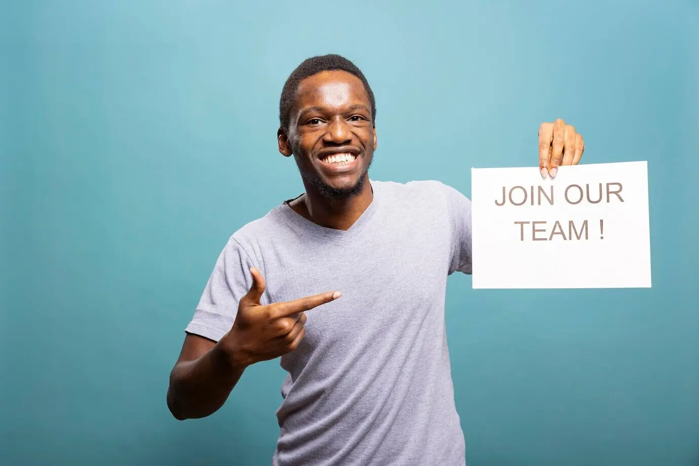 Fröhlicher Recruiter zeigt auf ein Einstellungsschild.